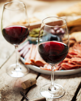 Two wine glasses filled with red wine. In the background, a traditional wine tavern snack