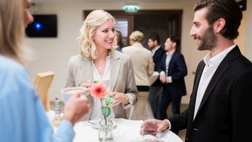 Seminar guests chat at the bar table in the seminar hotel Schlaining.