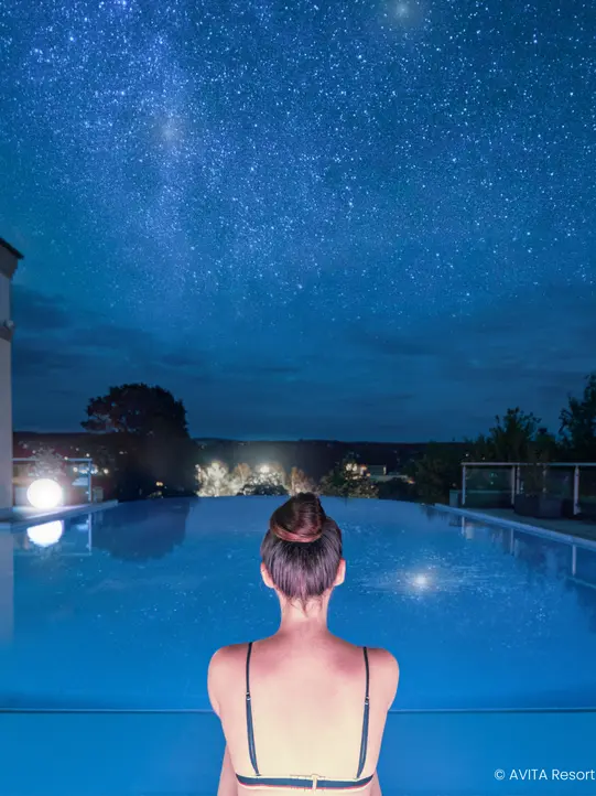 Woman in the infinity pool at night.
