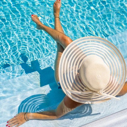 Lady with a sun hat on a lounger in the pool.
